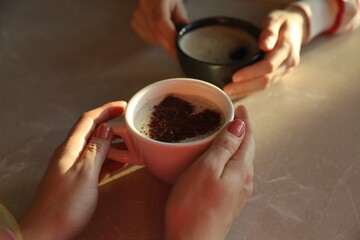 Women with cups of hot coffee at grey table, closeup
