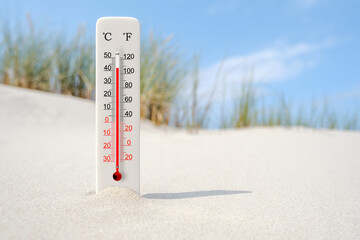 Hot summer day. Celsius and fahrenheit scale thermometer in the sand. Ambient temperature plus 42 degrees - obrazy, fototapety, plakaty