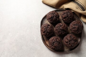 Board with delicious chocolate muffins on light table, top view. Space for text