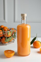 Bottle with tasty tangerine liqueur and fresh citrus fruit on white table