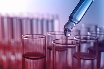 Dripping reagent into test tube with sample, closeup. Color toned