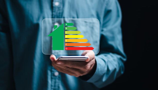 Energy efficiency concept. Person use smartphone with virtual screen of energy efficiency rating for energy efficient house building rate label audit. - Powered by Adobe