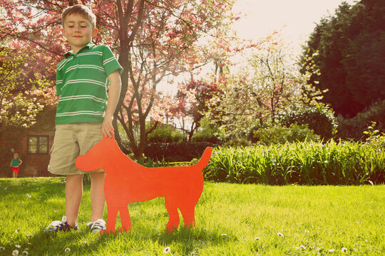 Young Boy Holding Cardboard Cut Out in Shape of Dog
