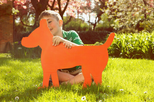 Young Boy Holding Cardboard Cut Out in Shape of Dog
