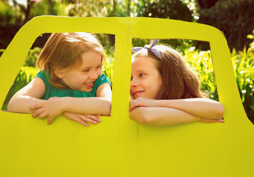 Young Girls Leaning out of Cardboard Car Window
