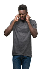 Young african american man wearing grey t-shirt covering ears with fingers with annoyed expression for the noise of loud music. Deaf concept.