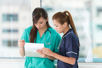 A team of two Asian medical staff checking a patients records