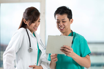 Two Asian doctors checking a patients records