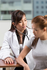 Chinese doctor checking female patient with a stethoscope