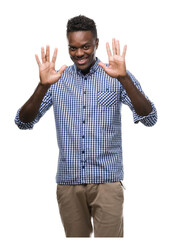 Fototapeta premium Young african american man wearing blue shirt showing and pointing up with fingers number ten while smiling confident and happy.