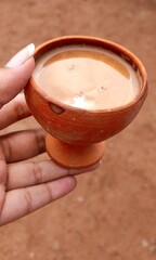 Milk tea in a clay mud cup held by a woman's hand