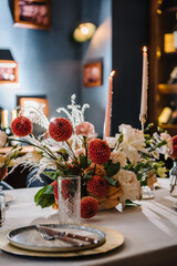 Festive dinner table decorated with flower and greenery, candles. Birthday celebration in restaurant. Serving, setting table. Plate, silverware cutlery, glasses. Wedding set up, reception closeup.