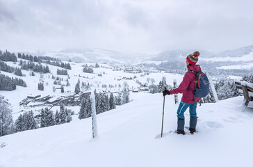 Fototapeta na wymiar nice and active senior woman hiking with snow shoes in deep powder snow in the Allgau alps, Bavaria, Germany