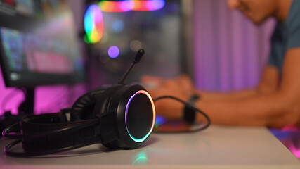 Close up of headset on desk with male gamer sitting in background. Gamer and technology concept © Prathankarnpap