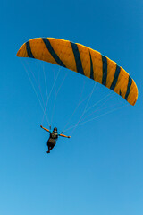 Paraglider flying over the sea coast in blue sky background