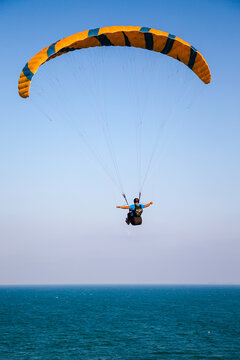 Paraglider flying over the sea coast in blue sky background