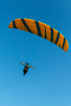 Paraglider flying over the sea coast in blue sky background