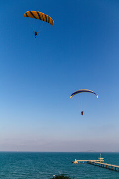 Paraglider flying over the sea coast in blue sky background