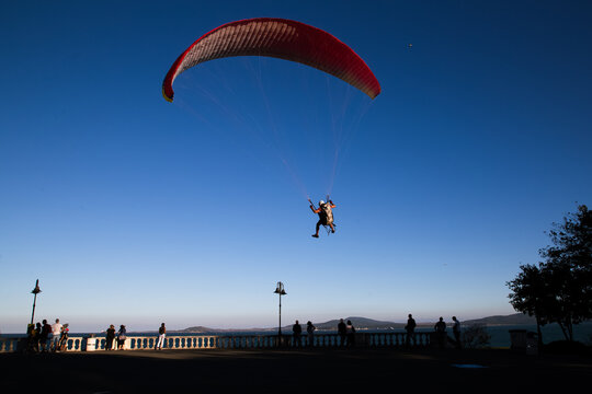 Paraglider flying over the sea coast in blue sky background