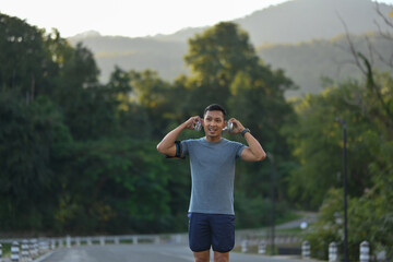 Active sporty man listening to music through headphones while running in the morning