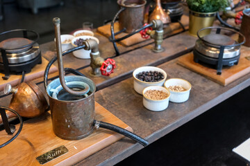 Small copper stills and distilling equipment arranged on a decorated table.