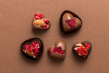 chocolate sweets in the form of a heart with fruits and nuts on a colored background. top view with space for text, holiday concept
