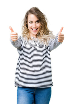 Beautiful young blonde woman wearing stripes sweater over isolated background approving doing positive gesture with hand, thumbs up smiling and happy for success. Looking at the camera