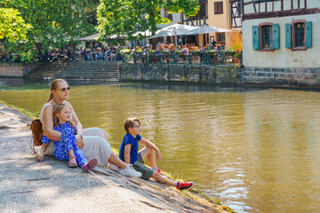 A happy family relaxes on the river bank. Alsace, France. Traditional half-timbered houses on the canals district La Petite France in Strasbourg in summer.