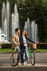 Obraz premium Beautiful couple with bicycles spending time together in park