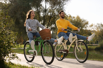 Obraz premium Beautiful young couple riding bicycles in park
