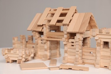 Wooden entry gate and building blocks on white table against grey background, closeup. Children's...