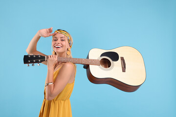 Happy hippie woman with guitar on light blue background