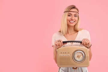 Portrait of happy hippie woman with retro radio receiver on pink background. Space for text