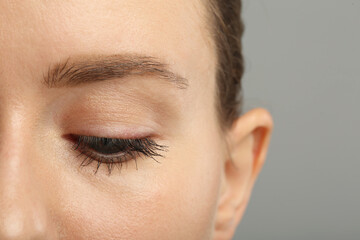 Naklejka premium Woman with long eyelashes after mascara applying against grey background, closeup