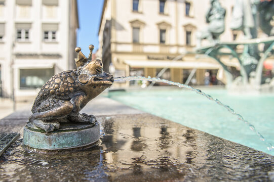 Brunnenskulptur Froschk&ouml;nig mit Wasserstrahl vor H&auml;userkulisse am Marktbrunnen in Ehingen an der Donau