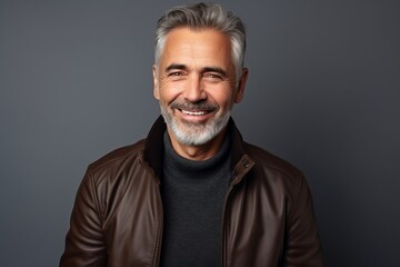 Portrait of a smiling mature man in a leather jacket against grey background