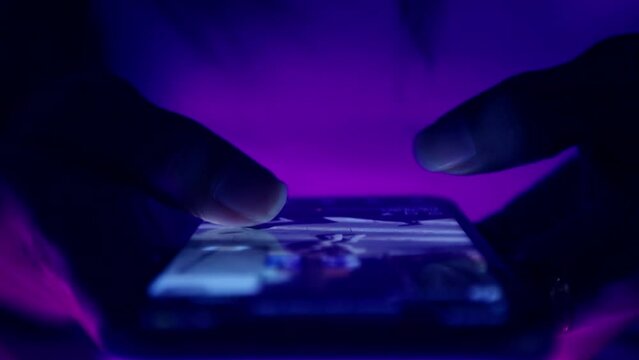 Finger of woman touching scroll page app on mobile phone.In a room with blue and purple neon tones.concept Social media and marketing