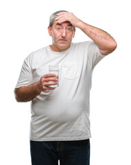 Handsome senior man drinking glass of water over isolated background stressed with hand on head, shocked with shame and surprise face, angry and frustrated. Fear and upset for mistake.