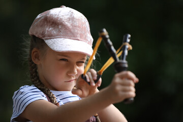Little girl playing with slingshot in park