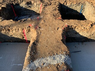 Isolated concrete footings for new buildings under construction. Holes filled with lean concrete before foot foundation.