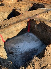 Vertical shot of a isolated concrete footings for new buildings under construction. Holes filled with lean concrete before foot foundation.