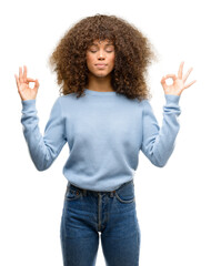 African american woman wearing a sweater relax and smiling with eyes closed doing meditation gesture with fingers. Yoga concept.