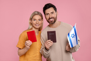 Immigration. Happy couple with passports and flag of Israel on pink background