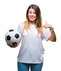 Young beautiful woman holding soccer ball over isolated background with surprise face pointing finger to himself