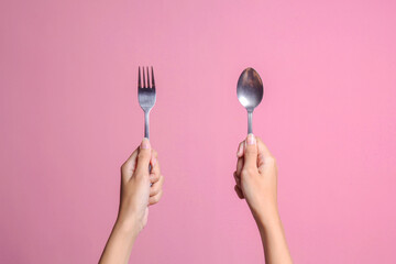 Woman hands showing spoon and fork isolated on pink color pastel background - obrazy, fototapety, plakaty