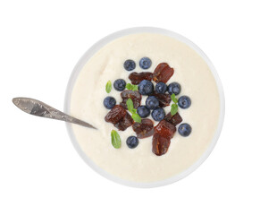 Delicious semolina pudding with blueberries, dates, mint and spoon in bowl isolated on white, top view