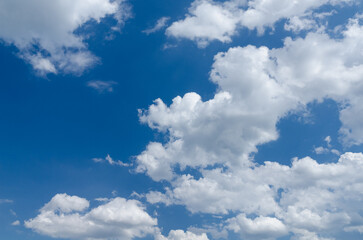 Naklejka na ściany i meble Fluffy white cumulus clouds in a blue sky on a beautiful day, natural soft background with copy space for text