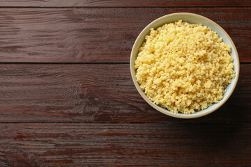 Tasty millet porridge in bowl on wooden table, top view. Space for text