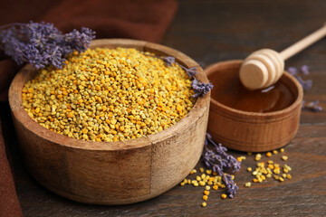 Fresh bee pollen granules, lavender, honey and dipper on wooden table, closeup