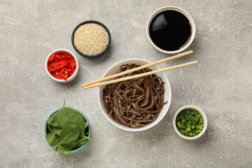 Tasty buckwheat noodles (soba) served on light grey table, flat lay